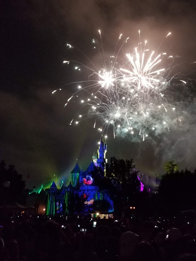 Fireworks explode at night over the lit up Disneyland castle. 