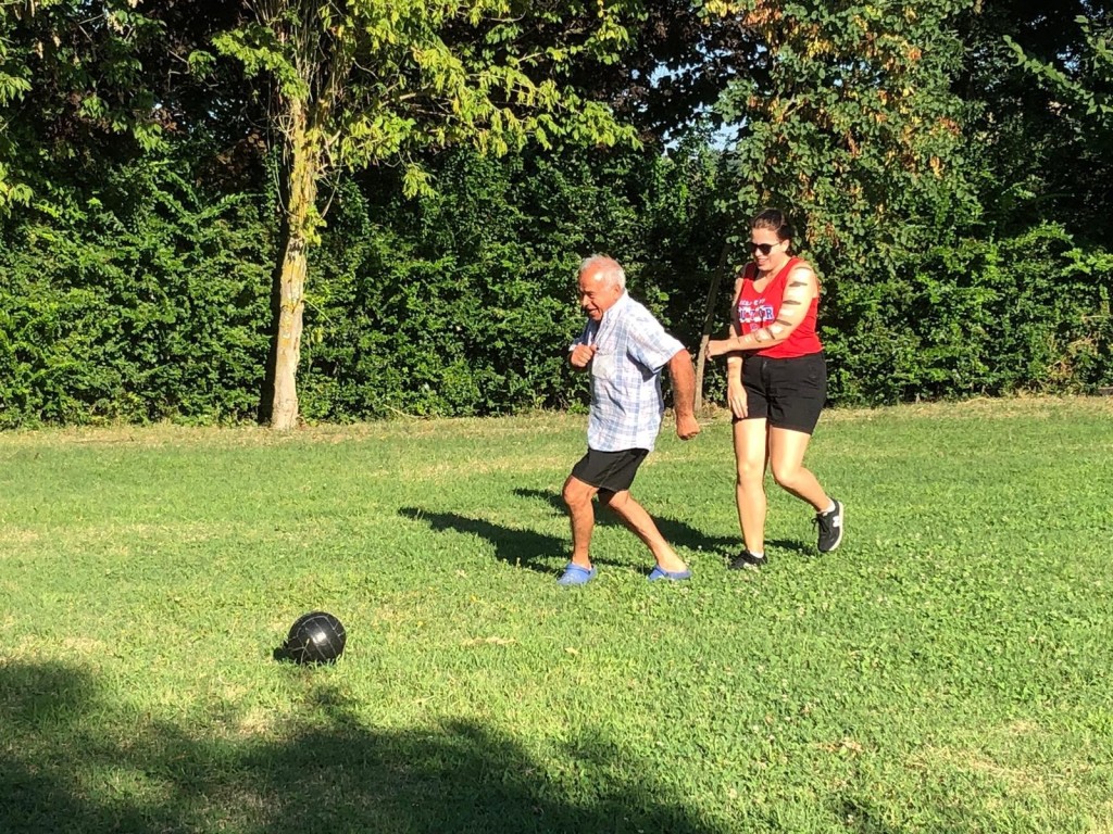Image shows an elderly Italian man quickly running after a soccer ball in a green field, outpacing the young college student author.